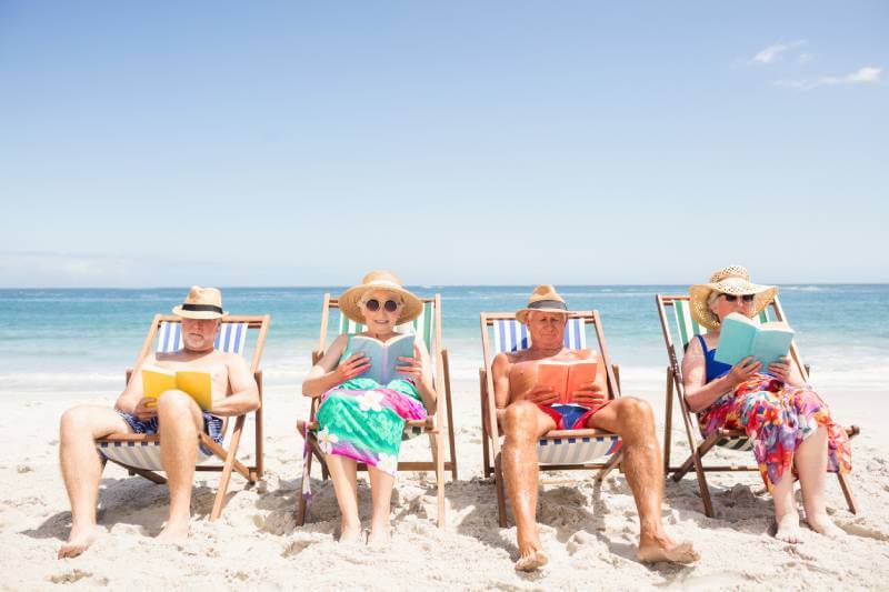 Seniors sitting on the beaching reading